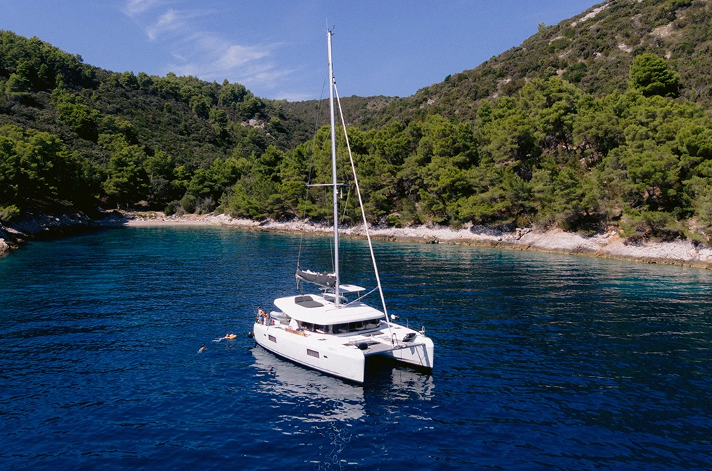 Катамаран Lagoon 42 «Orion» на якорі в тихій бухті біля соснового берега