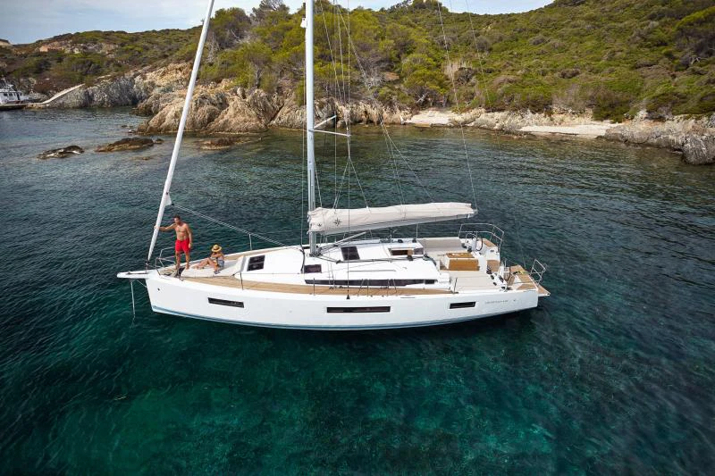 Вітрильна яхта Sun Odyssey 440 на якорі в прозорій зеленій бухті біля скелястого берега